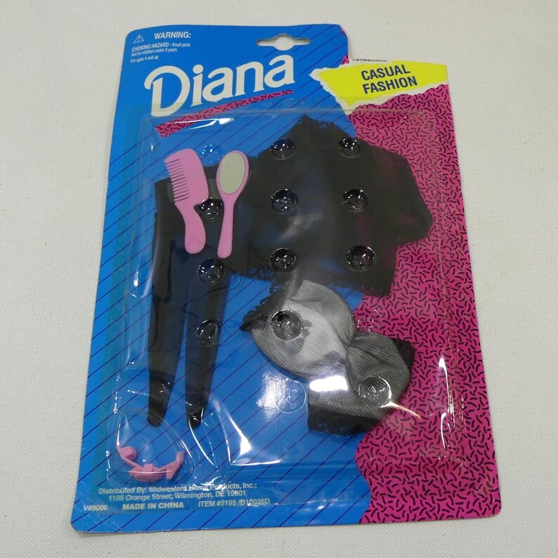 May include: A black and white doll outfit with a black top, white skirt, and a black headband. The outfit comes with a pink comb and a mirror. The packaging is blue and pink with the words "Diana" and "Casual Fashion".