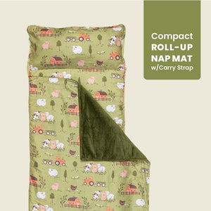 May include: A green and brown farm-themed nap mat with a plush green lining. The mat features a repeating pattern of pigs, cows, chickens, and tractors. The mat rolls up and has a carry strap. Compact Roll-Up Nap Mat w/Carry Strap.