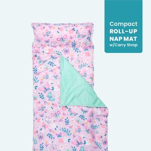 May include: A pink and purple roll-up nap mat with a butterfly and floral pattern. The mat includes a pillow and a mint green blanket. The text on the image reads "Compact ROLL-UP NAP MAT w/Carry Strap."