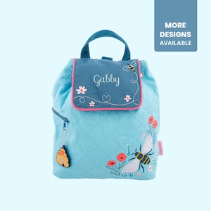 May include: A light blue quilted backpack with a bee and flower embroidery design. The backpack has a blue flap with the name "Gabby" embroidered on it.