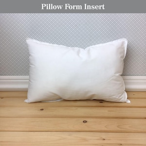 May include: A white pillow form insert, a type of stuffing for pillows, is shown on a wooden floor.