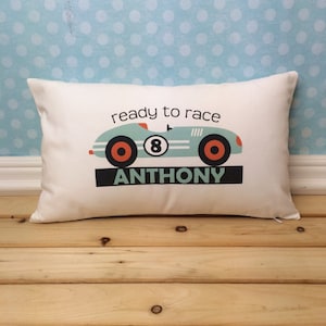 May include: A white pillow with a blue race car and the text "ready to race" and "ANTHONY".
