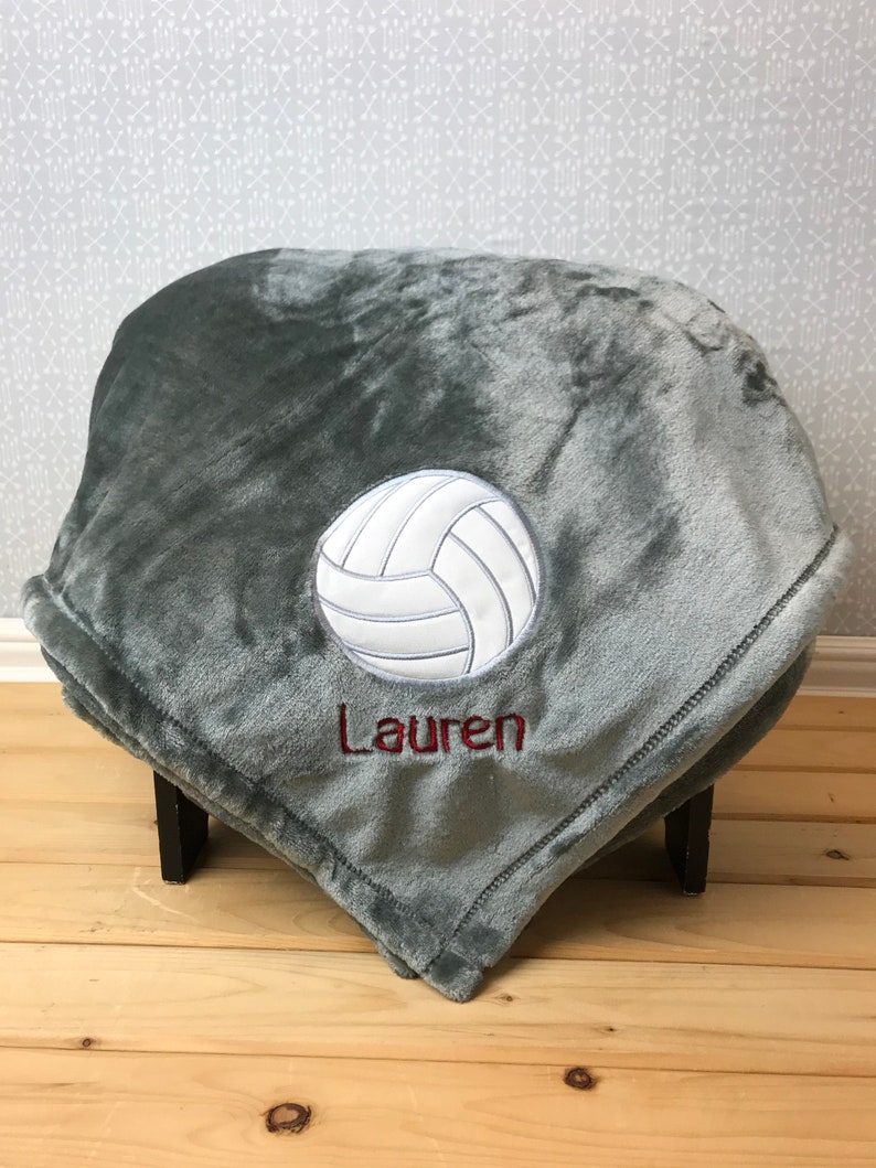 May include: Gray fleece blanket with a white volleyball and the name "Lauren" embroidered in red.