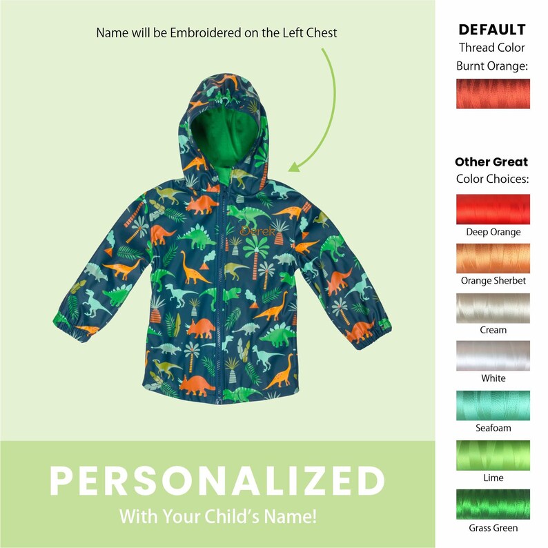 May include: A blue hooded raincoat with a dinosaur and palm tree print. The raincoat has a zipper closure and a green hood. The text "PERSONALIZED With Your Child's Name!" is at the bottom of the image. The text "DEFAULT Thread Color Burnt Orange:" is on the right side of the image with a swatch of burnt orange thread. The text "Other Great Color Choices:" is below the burnt orange swatch with swatches of different thread colours.