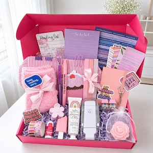May include: A pink gift box filled with stationery and self-care items including a reading list card, a purple to-do list, pink fuzzy socks, a cupcake notepad, a pen, body lotion, a white book light, a rose-shaped candle, and various stickers.