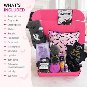 May include: A pink gift box containing gray fuzzy socks with ghost patterns, a pink makeup bag with black bats, a crochet bat, a black bat-shaped facial mask, a purple eye mask packet, a black scrunchie, a purple bath bomb, lip balm, and a bracelet.