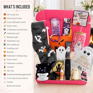 May include: A pink gift box containing Halloween-themed items including fuzzy gray ghost socks, a glass cup with a bamboo lid, a black makeup bag with a jack-o'-lantern face, a ghost facial mask, a black reading light, a crochet cat plush, and stationery.