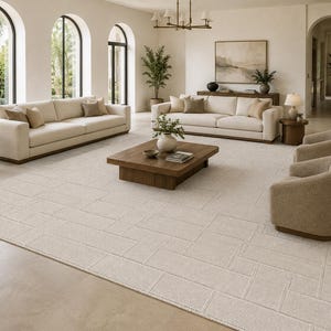 May include: A bright living room featuring cream-colored sofas, armchairs, and a patterned rug. A wooden coffee table is in the center, and a lamp sits on a side table. Large windows and arched doorways provide natural light.