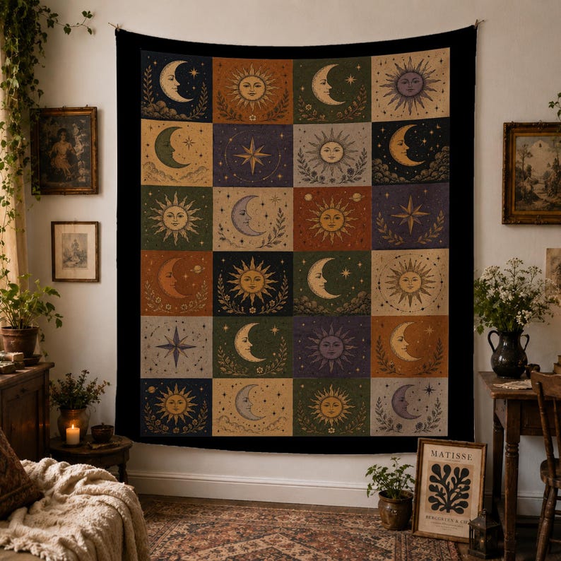May include: A large, black tapestry with a repeating pattern of celestial bodies. Each square features a sun, moon, or star design in shades of gold, orange, and blue. The tapestry is hanging on a white wall.