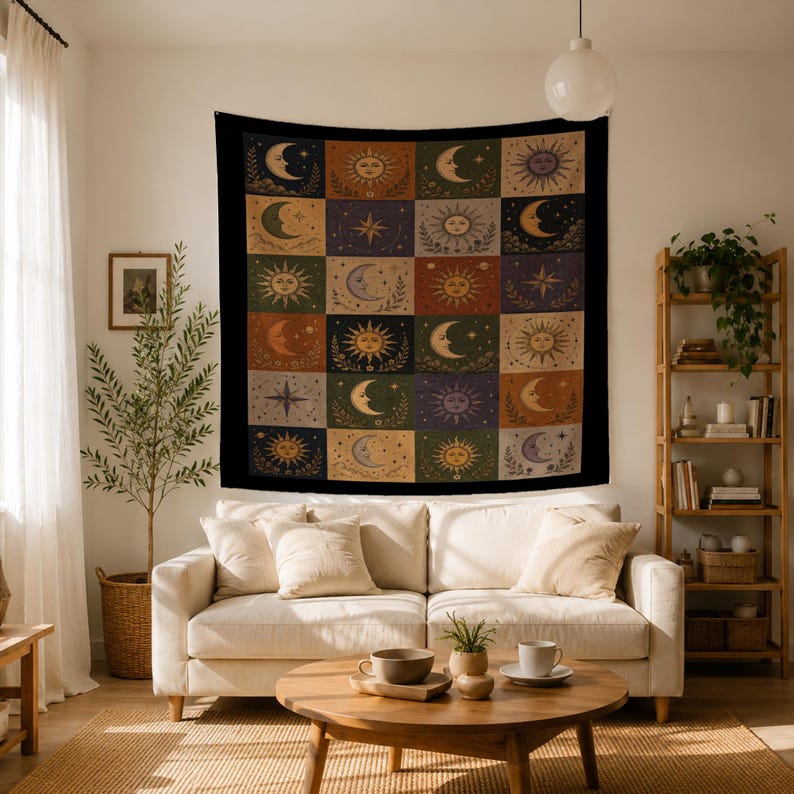 May include: A large, square tapestry with a black border, featuring a grid of celestial designs. Each square showcases a sun, moon, or star in shades of gold, orange, and purple against a dark background. The tapestry is hanging on a white wall.
