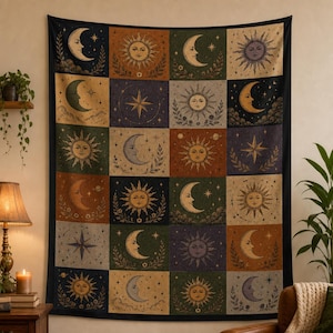 May include: A tapestry featuring a celestial design with suns, moons, and stars in a grid pattern. The artwork uses a palette of earthy tones, including brown, green, and gold, with a black border. The tapestry is likely used as wall decor.