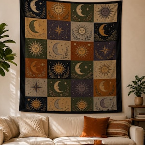 May include: A large tapestry with a black border, featuring a grid of celestial designs. Each square showcases a sun, moon, or star in various colors like gold, orange, and blue, set against a backdrop of green, purple, and beige.