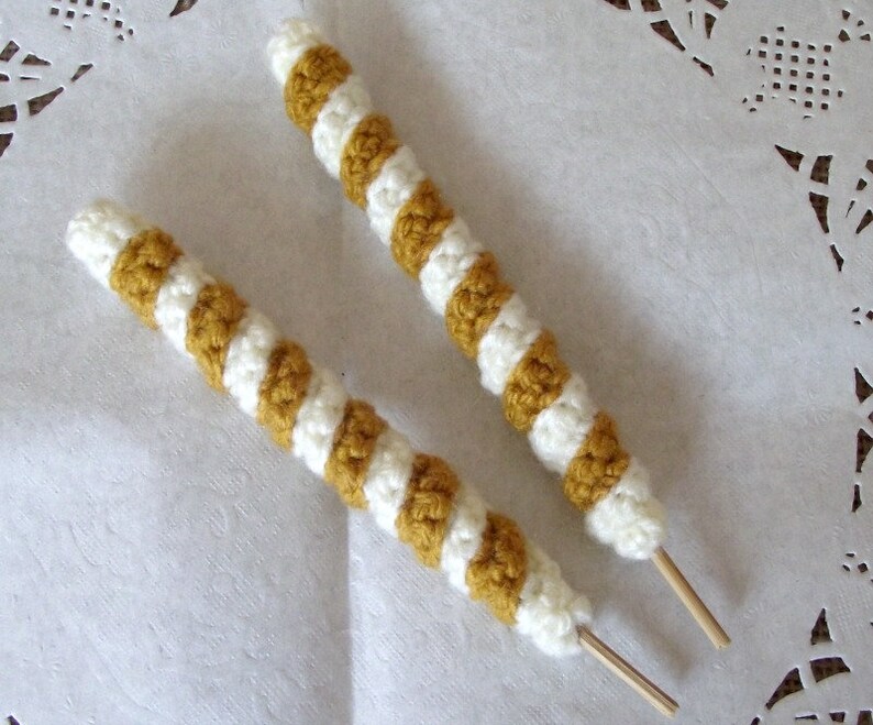 May include: Two crocheted striped cords in white and mustard yellow with wooden sticks attached to the ends.