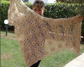 Puede incluir: Un chal de ganchillo beige con un patrón floral. El chal está hecho de hilo delicado y tiene una sensación ligera.