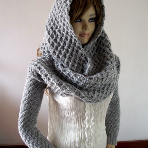 May include: A gray knitted cowl neck sweater with long sleeves and a waffle stitch pattern.