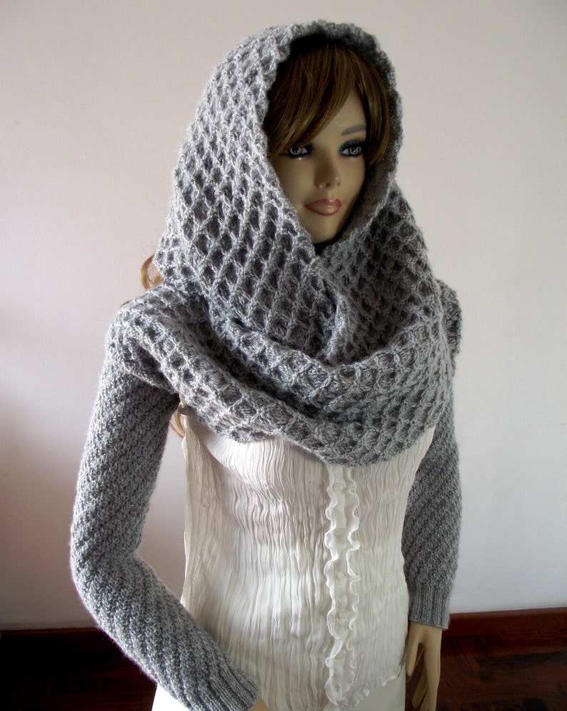 May include: A gray knitted cowl neck sweater with long sleeves and a waffle stitch pattern.