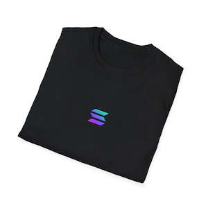 Peut inclure: T-shirt noir avec un petit logo stylisé en dégradé de bleu et de violet. Le logo est composé de trois lignes horizontales. Le t-shirt est plié, indiquant un tissu doux.
