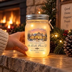 May include: A frosted glass mason jar with a silver metal lid and a twine bow, illuminated from within. The front features a printed image of a house in snow, with the text: First Christmas at 68 North Main St, The Smith Family, 2026.