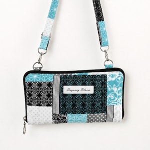 May include: A rectangular quilted crossbody bag featuring a patchwork design in shades of black, white, and turquoise blue. The bag has a zipper closure, a matching adjustable strap, and a white label with the text Dayoung Bloom.