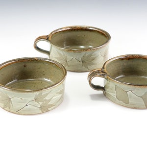 May include: Three ceramic soup bowls with handles. The bowls are green with a brown rim and a leaf design.