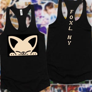 May include: Black vest top with a cream-coloured fox graphic on the front. The fox design has large ears and is peeking over a black rectangle. The back of the vest top has the word "FOX L. N Y" printed vertically in a cream colour.