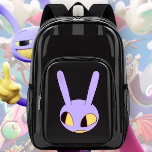 Puede incluir: Una mochila negra brillante con un gráfico grande y centrado de una cabeza de personaje similar a un conejo morado con ojos amarillos. La bolsa incluye un bolsillo frontal con cremallera, correas negras y bolsillos laterales de malla.