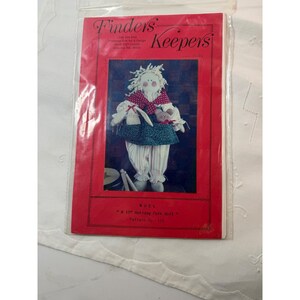 May include: A Finders Keepers sewing pattern packet for a 15 inch holiday folk doll named Noel. The red cover features a photograph of a fabric doll with white yarn hair, a red and white polka dot collar, a green dress, and striped pants.