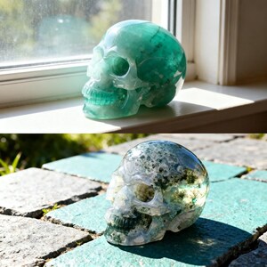 May include: Two carved crystal skulls. The top skull is a translucent teal color, and the bottom skull is a mix of green and white. Both skulls are displayed in natural light, showcasing their intricate details and polished surfaces.