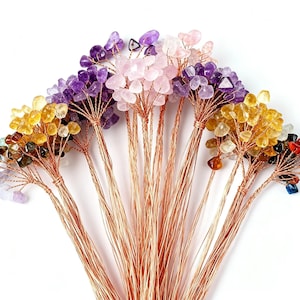 Könnte beinhalten: Eine Sammlung von Edelsteinbäumen mit Kupferdrahtästen und -stämmen. Die Bäume zeigen Cluster aus Amethyst, Rosenquarz, Citrin und anderen farbigen Steinen. Die Bäume sind vor einem weißen Hintergrund angeordnet.