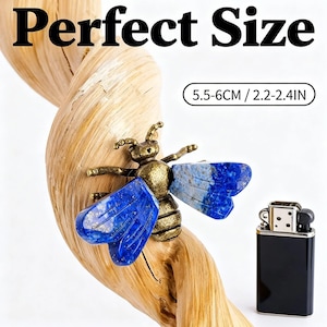 May include: A bee-shaped ornament with a metallic bronze-toned body and deep blue lapis lazuli wings. The item is displayed on a twisted piece of light-colored wood next to a black lighter. Text on the image reads Perfect Size 5.5-6CM / 2.2-2.4IN.