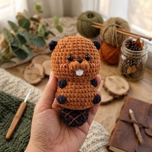 May include: A set of three ceramic mugs with a speckled, cream-colored glaze. Each mug features a different hand-painted design: a blue and green leaf, a yellow flower, and a red berry. The mugs have a simple, rounded shape.