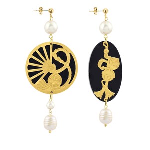 May include: A pair of gold-colored earrings with black and white accents. One earring is a circular design with a fan-like pattern, and the other is an oval shape. Both earrings feature dangling pearls.