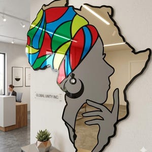 Puede incluir: Un espejo de pared decorativo con la forma del continente africano. La parte superior es un mosaico de formas coloridas, mientras que la mitad inferior presenta el perfil de una persona. El espejo tiene un contorno negro y una superficie reflectante.