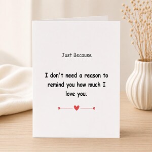 Könnte beinhalten: Eine weiße Grußkarte mit schwarzem Text, der lautet Just Because, I don't need a reason to remind you how much I love you. Unter dem Text befindet sich ein kleines rotes Herz, das zwischen zwei dünnen roten Linien auf der Karte steht.