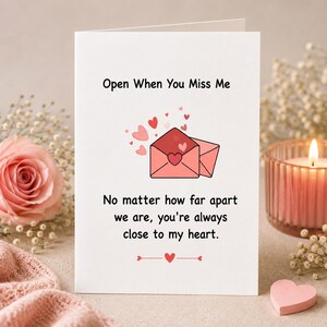 May include: A white greeting card with the black text Open When You Miss Me at the top and a pink envelope illustration surrounded by small hearts. Below is the text No matter how far apart we are, you're always close to my heart with a heart icon.