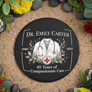 Può includere: Una targa rotonda in ardesia nera con il testo bianco DR. EMILY CARTER, 1980, 2025 e 45 Years of Compassionate Care. Il design include un'illustrazione bianca di un camice da medico con uno stetoscopio e un emblema a croce medica rossa.