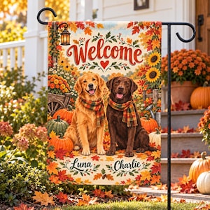 Può includere: Una bandiera da giardino rettangolare con un golden retriever e un labrador color cioccolato che indossano sciarpe a quadri. Il testo Welcome è in alto, mentre i nomi Luna e Charlie sono in basso, tra zucche e foglie autunnali.