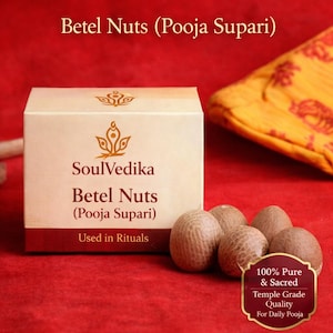 May include: A box of SoulVedika Betel Nuts (Pooja Supari) with the text "Used in Rituals." The box is beige with a maroon base, and the text is in brown. Several brown betel nuts are next to the box, with a label that reads "100% Pure & Sacred."