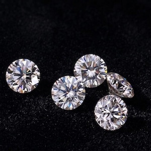 Peut inclure: Cinq diamants ronds à facettes brillantes sont présentés sur un fond noir. Les diamants scintillent, reflétant la lumière de leurs nombreuses facettes. Les pierres précieuses varient en taille, soulignant leur clarté et leur brillance.