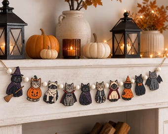 Może przedstawiać: Girlanda na Halloween z dziesięcioma drewnianymi wycinankami kotów w różnych kostiumach, w tym czarownicy, dyni, mumii, wampira, szkieletu i nietoperza, połączonymi białymi drewnianymi koralikami na naturalnym sznurku.