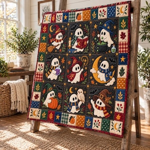 May include: A rectangular quilt featuring nine square panels with white ghost illustrations on a dark background, surrounded by a colourful border of small squares with patterns of pumpkins, stars, leaves, and berries in autumn colours.