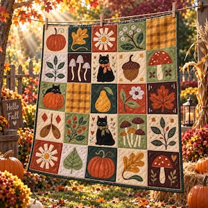 Op de afbeelding: Een gewatteerde sprei met een raster van twintig vierkanten met herfstthema-illustraties, waaronder pompoenen, zwarte katten, paddenstoelen, eikels, bladeren, bloemen en ruitpatronen in tinten oranje, groen, bruin en crème.