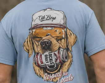 Könnte beinhalten: Ein hellblaues T-Shirt mit einer Grafik eines Golden Retrievers, der eine weiße Kappe mit der Aufschrift Ole Boys und orangefarbene Sonnenbrille trägt. Der Hund hält eine Bierdose mit der Aufschrift Locals Only, darunter steht Respect the Locals.