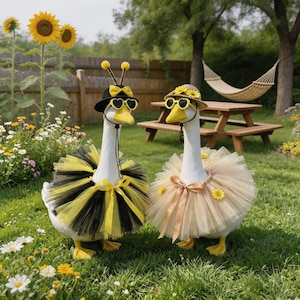 May include: Two geese dressed in whimsical costumes stand in a garden. One wears a black and yellow tutu, sunglasses, and a hat with antennae. The other is in a tan tutu, sunglasses, and a straw hat. A picnic table and hammock are in the background.