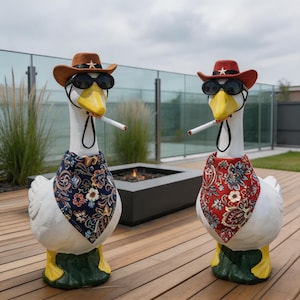 May include: Two white goose statues with yellow beaks and feet, wearing cowboy hats, sunglasses, and bandanas. One bandana is navy with floral patterns, the other is red with paisley. Each goose has a cigarette in its beak.