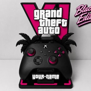 Può includere: Un supporto nero per controller di gioco con un logo rosa di Grand Theft Auto V, due sagome di palme e una targhetta personalizzabile. Il supporto include il testo Black Edition nell'angolo in alto a destra e your-name sulla base.