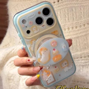 May include: A clear phone case with a light blue and yellow border, featuring a whimsical design of cartoon cats, pastries, and milk bottles. The case includes a matching pop-up grip with similar illustrations and the text "LZCoverDesign".