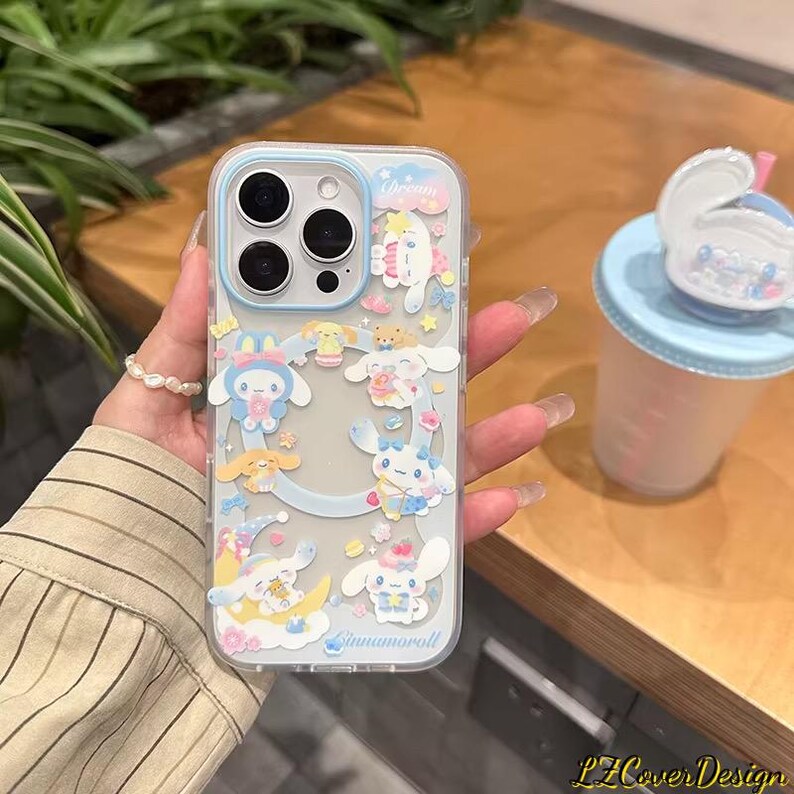 May include: Clear phone case with a light blue border and a variety of cartoon characters. The case features a design with clouds, stars, and the word "dream". The phone case is decorated with the characters "Cinnamoroll".