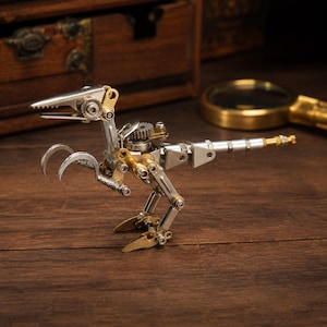 May include: A small dinosaur figurine constructed from various metal components including silver-toned gears, screws, bolts, and brass-colored accents. The figure features a sharp, articulated jaw, curved claw-like arms, and a long, segmented tail.