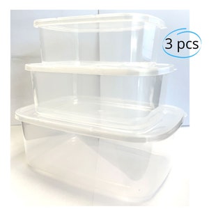 May include: A set of three clear, rectangular food storage containers with white lids. The containers are stacked, with the largest at the bottom and the smallest at the top. The text "3 pcs" is in a blue circle.